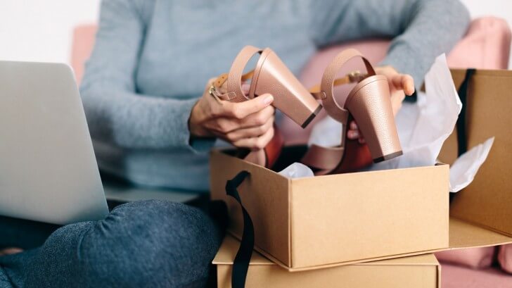 A woman takes soome high heeled sandals out of a cardboard box
