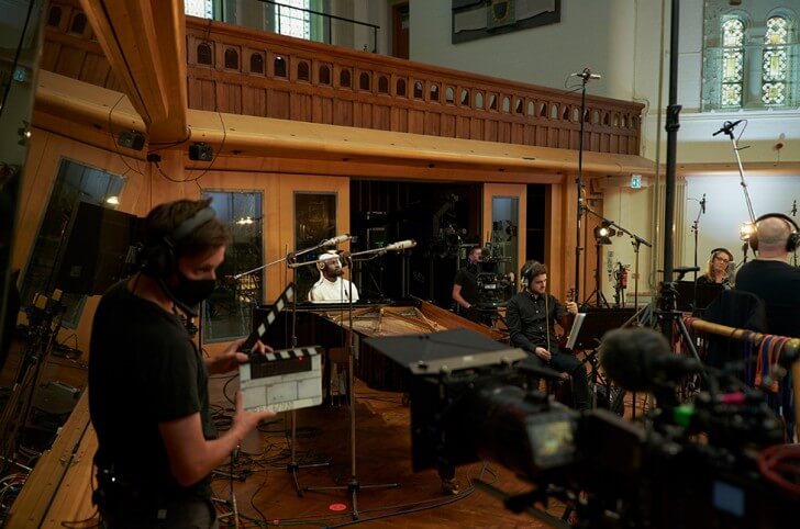 Filming crew in front of an orchestra in a studio