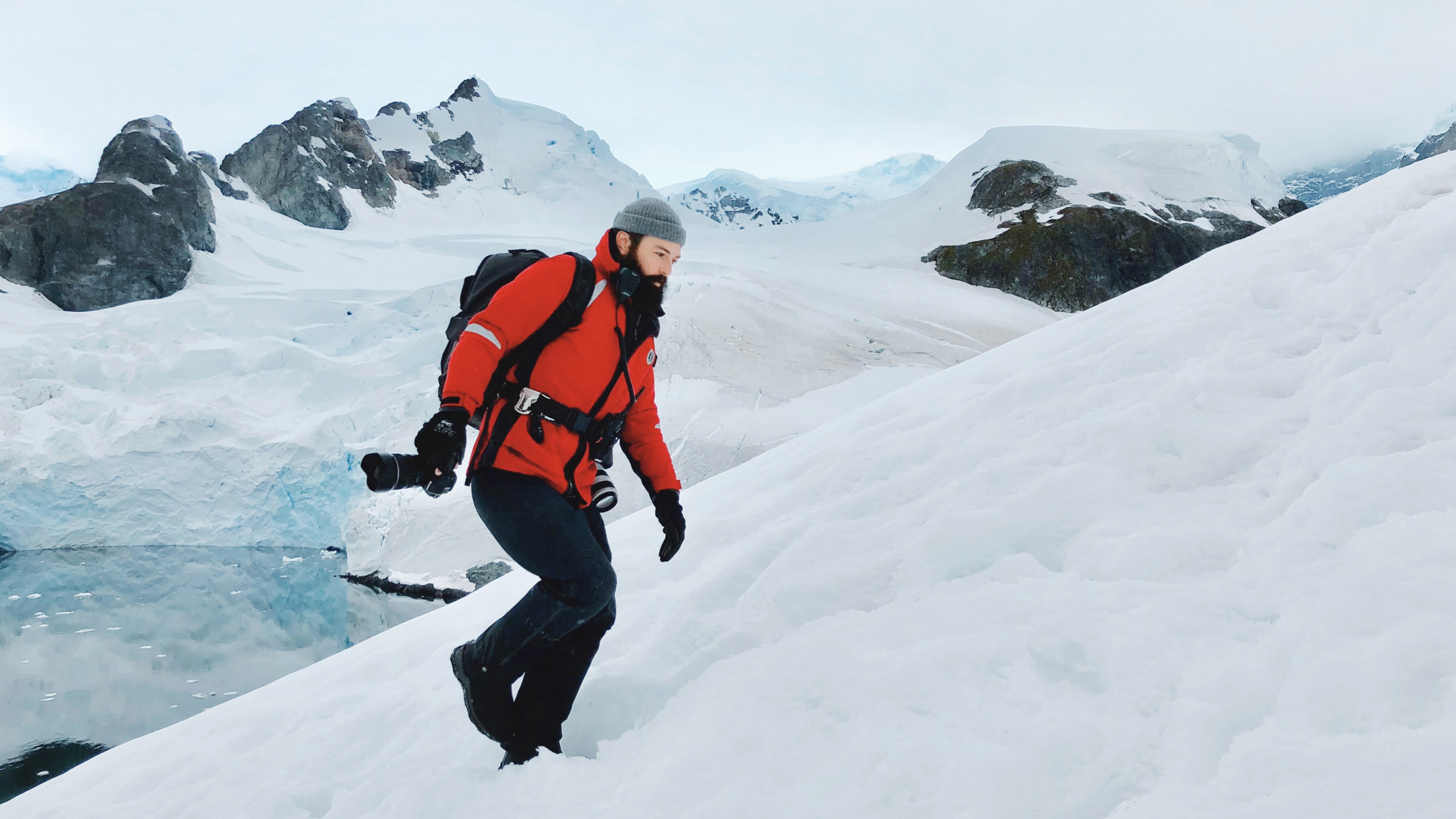 Photographer John Bozinov wears red jacket and walks in the snow and ice in the polar regions