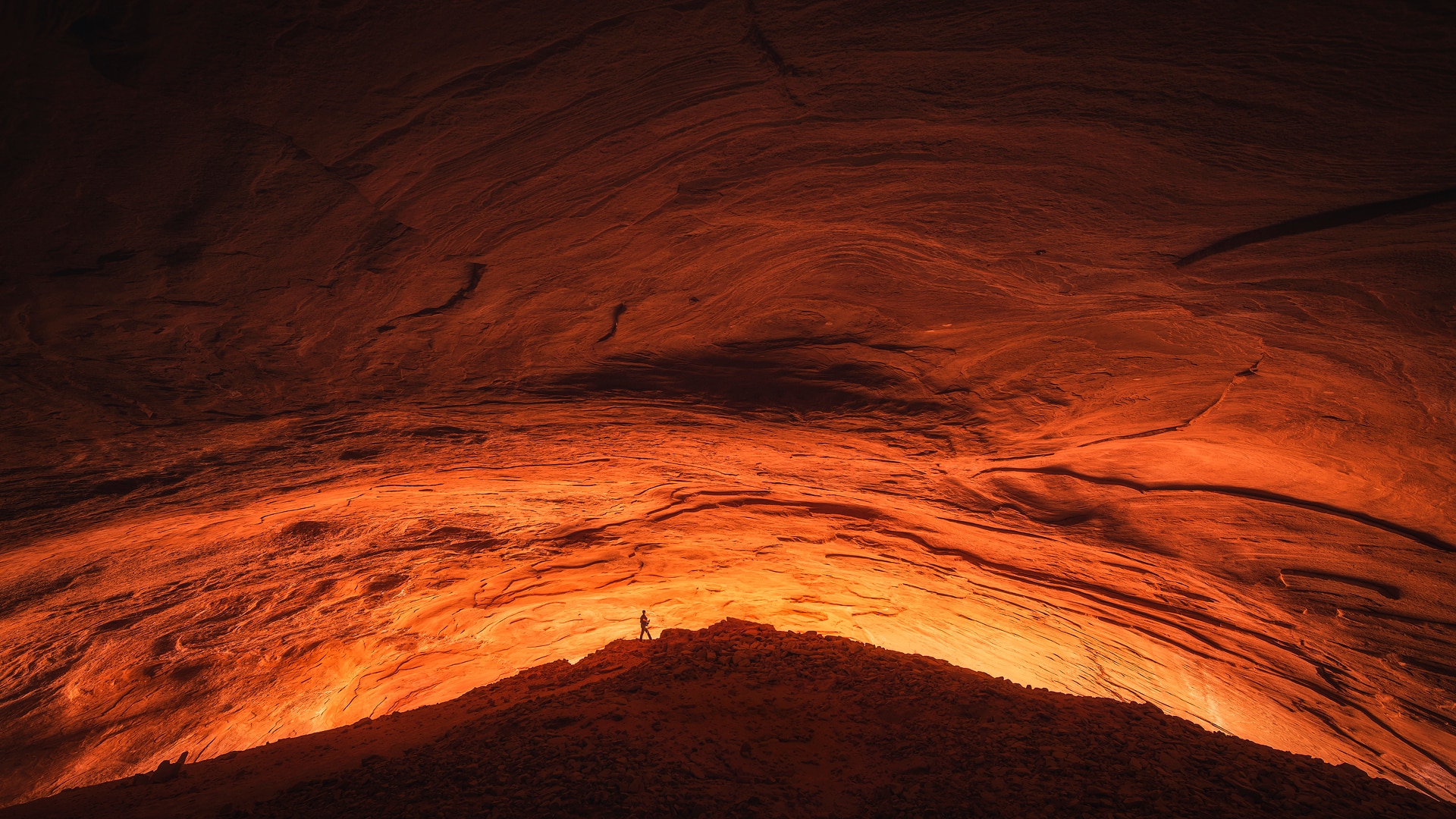 A lone figure, silhouetted against orange sandstone.
